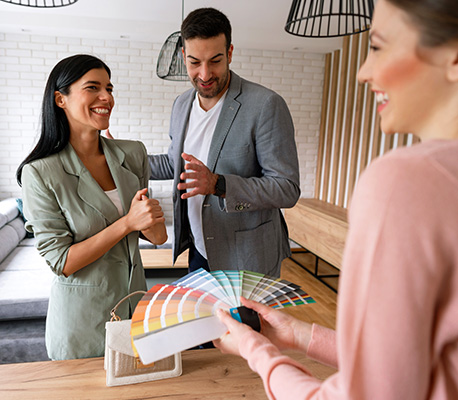 Young Caucasian couple looking at color swatches on a meeting with an interior designer, talking about a home interior.